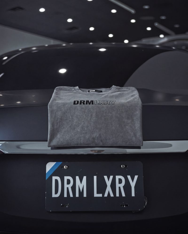 DRMLXRY Spec Sheet Tee folded above a DRM LXRY license plate